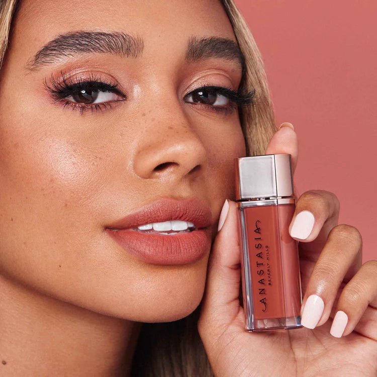 Model with nude lipstick holding Anastasia Beverly Hills velvet liquid lipstick