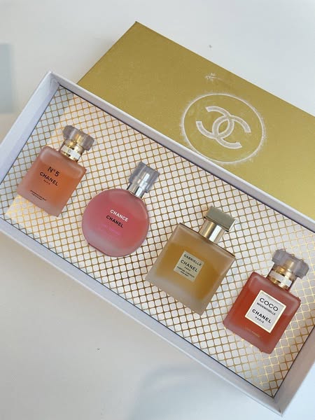Set of four Chanel perfume bottles in a branded box on a white background