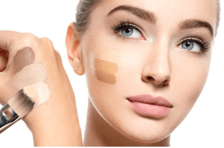 Woman applying makeup with a brush on a white background